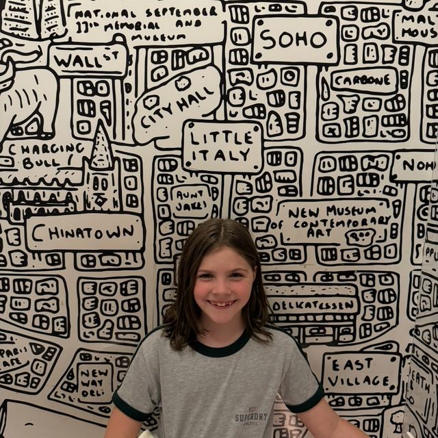 Grayscale photo of a girl in front of a hand-drawn NYC map mural